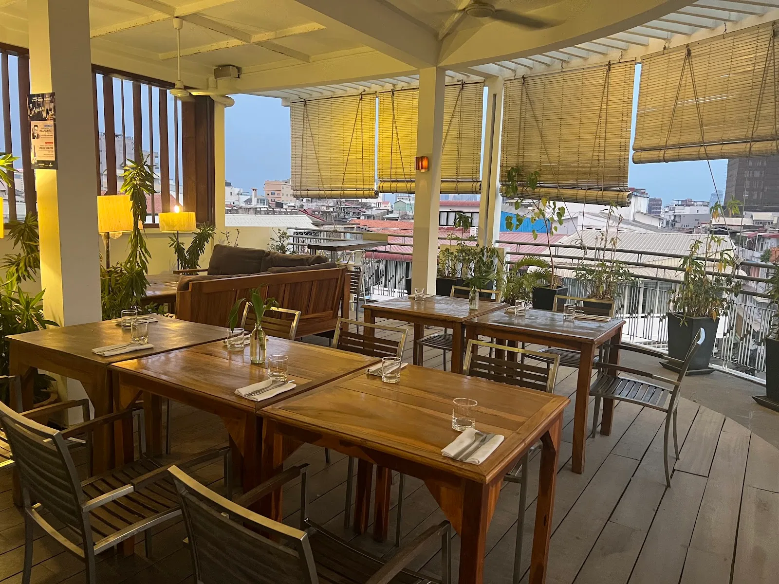Terrasse en rooftop, tables dressées face aux toits de Phnom Penh